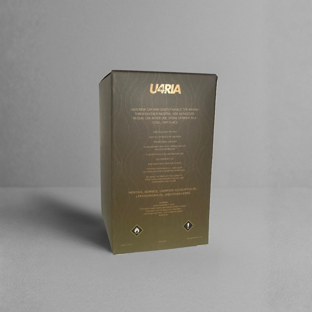 A tall rectangular product box standing upright on a light gray surface against a gray background. The box is yellow black gradient with metallic gold foil branding reading 'U4RIA' at the top and smaller gold text below, plus small black warning-style icons near the bottom.