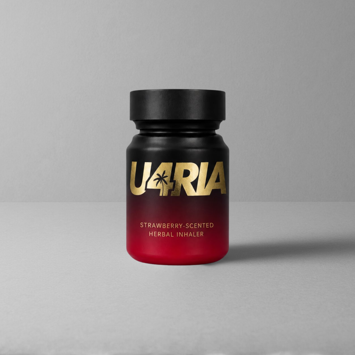 A matte black bottle of U4RIA strawberry scented herbal inhaler with a red gradient base and gold lettering, set against a neutral grey background.