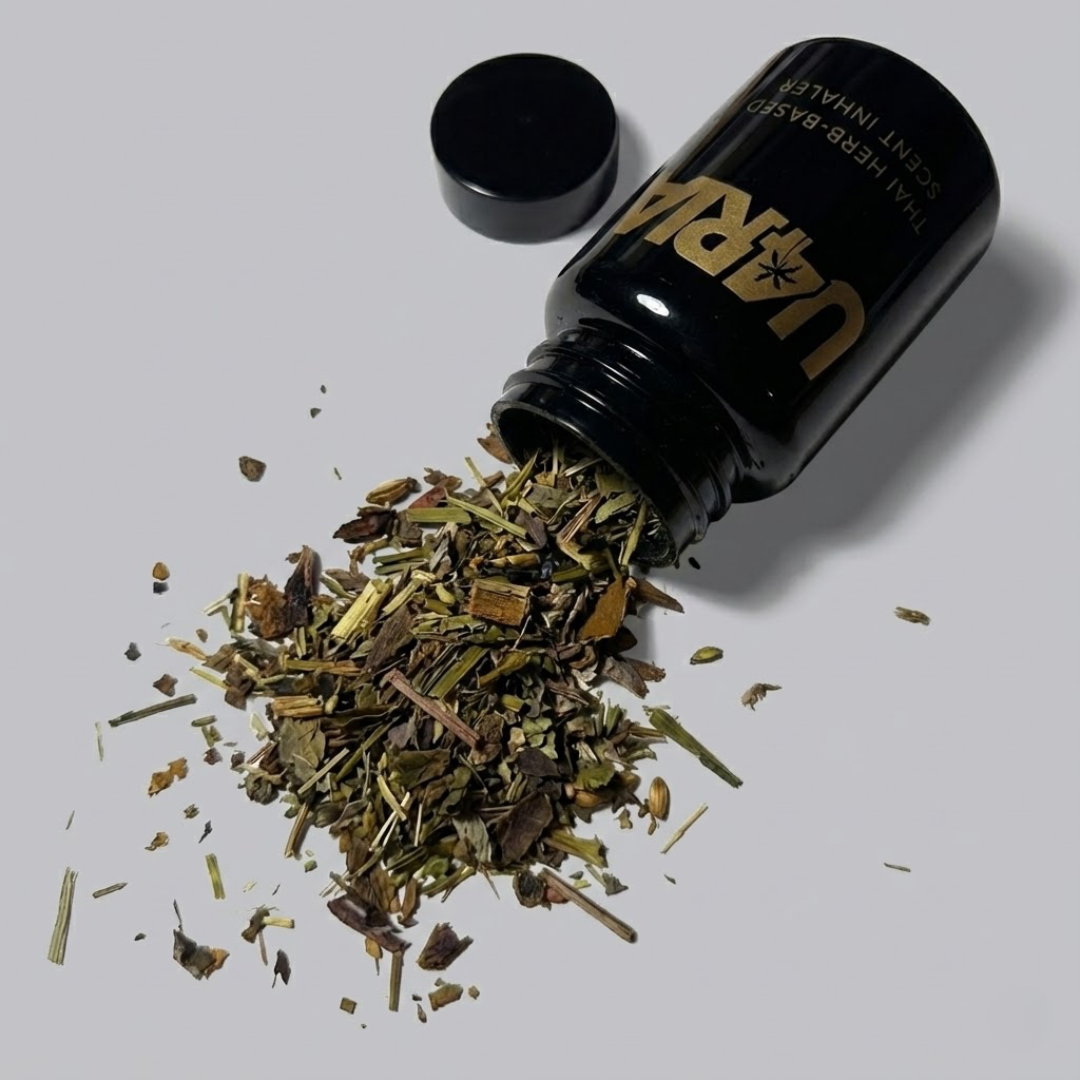 Black bottle with gold text containing spilled dried herbs on a light gray background
