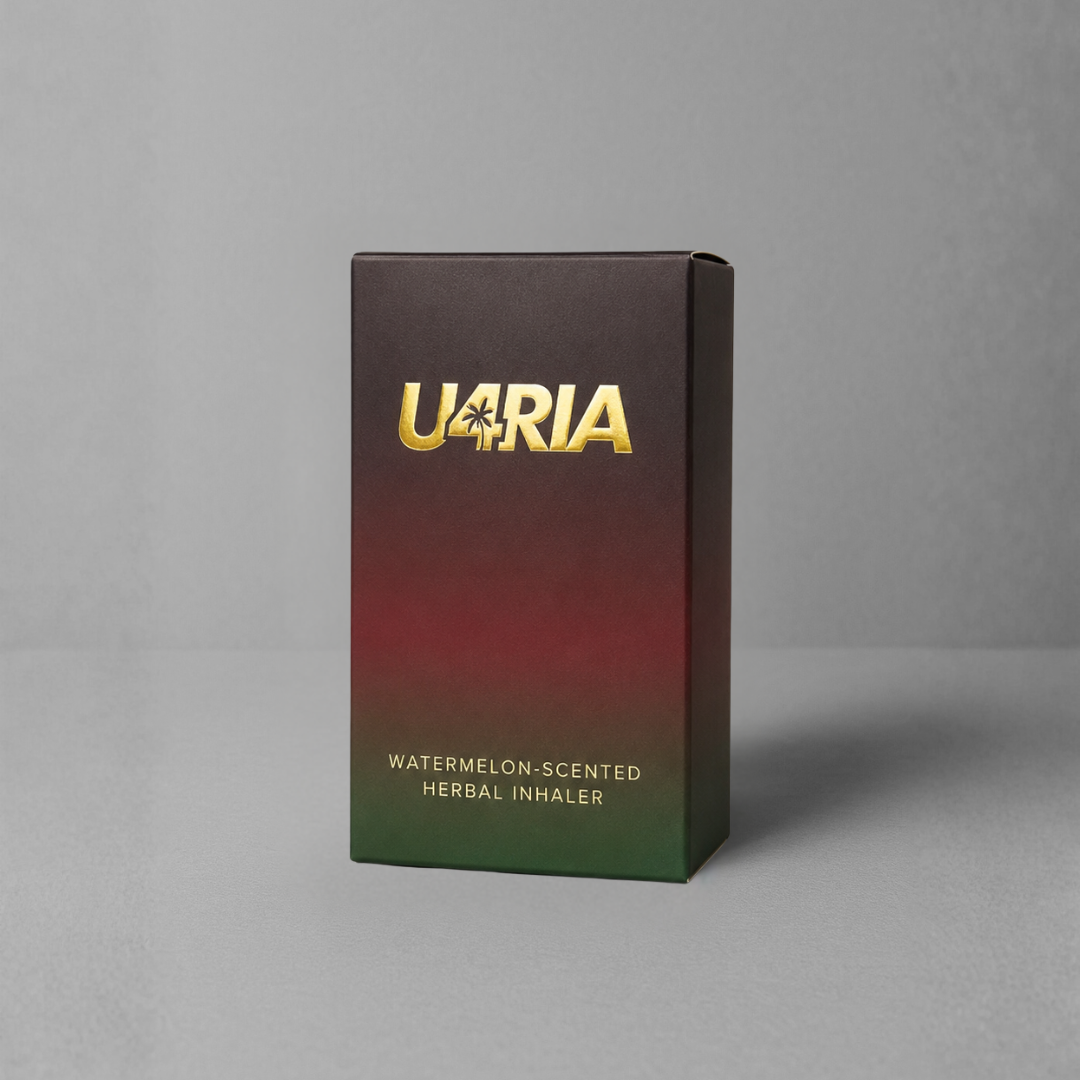 A rectangular product box for a U4RIA watermelon-scented herbal inhaler, standing upright on a grey surface against a grey background. The box features a dark gradient design transitioning from black at the top to red in the middle and green at the bottom, with the brand name 'U4RIA' in metallic gold lettering.